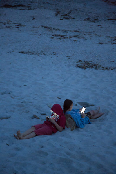 Dos à dos sur la plage, chacun concentré sur sa tablette numérique