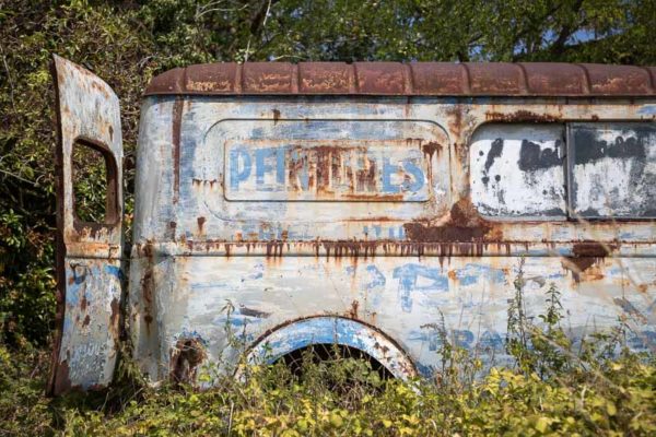 Camionnette d'une entreprise de peinture abandonnée dans la nature, rouillée.